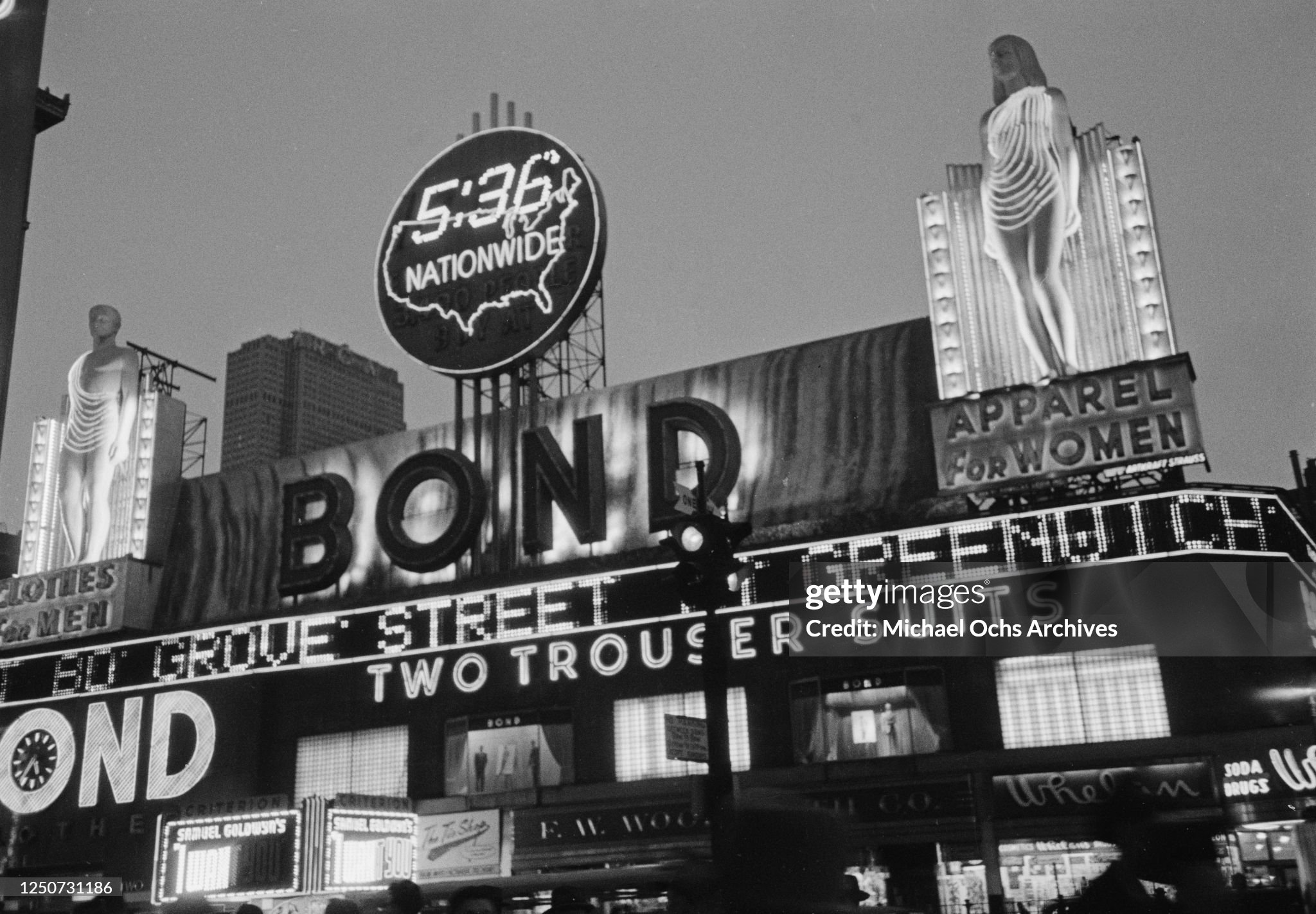 Bond sign illuminated at night with neon-clothed statues
